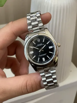رولكس ROLEX كلاسيك  ساعة رجالية بتصميم كلاسيكي، وسوار معدني بلون فضي وإطار دائري ناعم. مينا بسيط