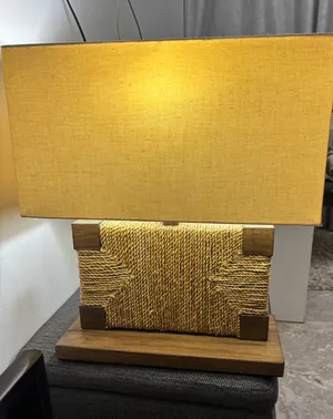أباجورة أو مصباح طاولة (Table Lamp)، وتتميز بتصميم خشبي ريفي (Rustic) مزين بحبل ملفوف يحيط بالقاعدة