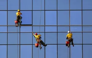 خدمه تنظيف واجهات المباني باستخدام الحبال.