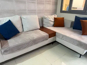 Beige 3 seater L shaped sofa with coffee table attached.