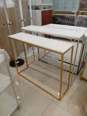 طاولة كونسول عصرية بتصميم هندسي نحيف وقاعدة معدنية ذهبية مع سطح أبيض أنيق