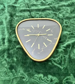 ساعة جدارية (Wall Clock) بتصميم عصري وأنيق، وتتميز بشكل مثلث ذو زوايا دائرية