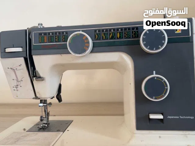 ماكينة خياطة جانومي طراز 393، وتتميز بهيكل معدني متين ولون أبيض مع تفاصيل رمادية./