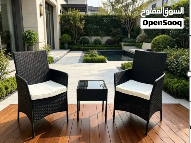 كرسيان من الراتان الأسود المتين مع وسائد بيضاء ناعمة ومقاومة للماء  طاولة وسط بسطح زجاجي آمن وقاعدة