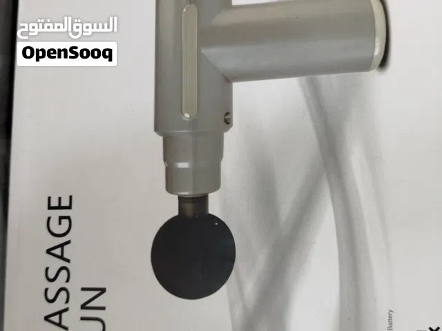 الصورة فيها علبة لجهاز *مسدس مساج Massage Gun*   *تفاصيل العلبة:* - *اللون*: أبيض مع رسمة رمادية ناع