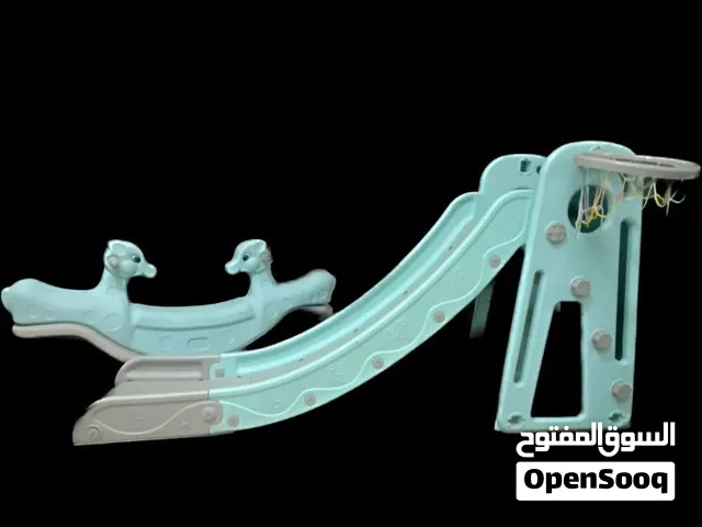حصان هزاز و زلاقة مزودة بحلقة كرة سلة مدمجة.  A rocking horse and a slide with a basketball hoop.