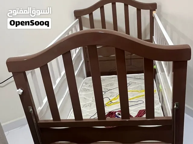 سرير أطفال خشبي أبيض وبني مع عجلات ومساحة تخزين