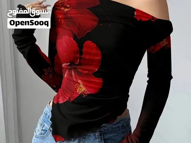 black long-sleeve top featuring a red tropical floral print, an off-the-shoulder neckline, and an as