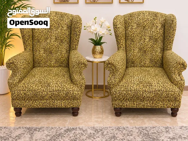كرسيان بتصميم كلاسيكي مميز ونقشة أنيقة باللون الذهبي والبني، مع مساند جانبية مريحة وأرجل خشبية