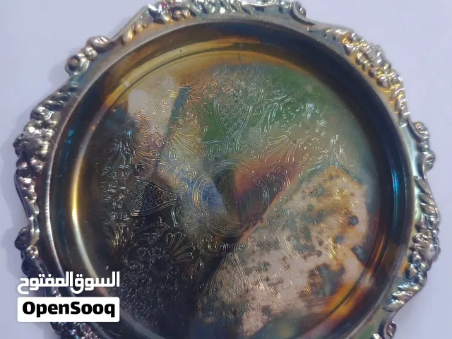 القطعة عبارة عن صحن صينية نحاسية زخرفية دائرية ذات حافة مرتفعة ومزخرفة بشكل كثيف