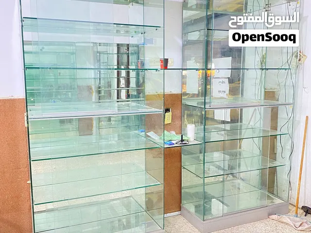 هذه فترينة عرض زجاجية طويلة، فيها عدة رفوف زجاجية وقاعدة سفلية