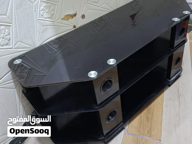 طاولة تلفزيون عصرية مكونة من ثلاثة أرفف سوداء مصنوعة من الزجاج المعالج (المقسّى) ومدعومة بهياكل جانب
