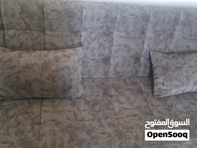 كنب رمادي قابل للتحول لسرير مع اثنين وسائد