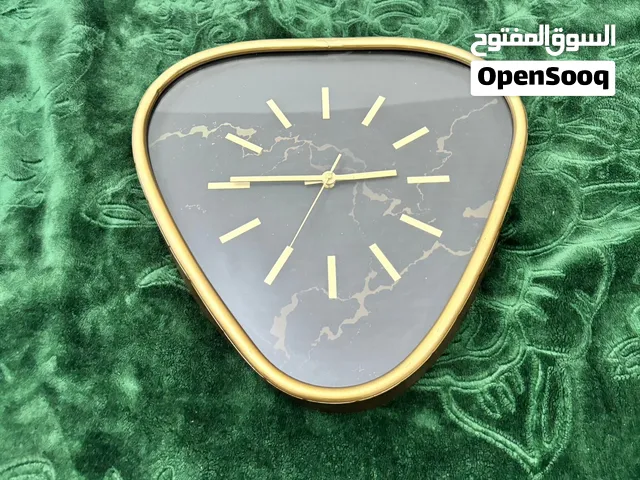ساعة جدارية (Wall Clock) بتصميم عصري وأنيق، وتتميز بشكل مثلث ذو زوايا دائرية